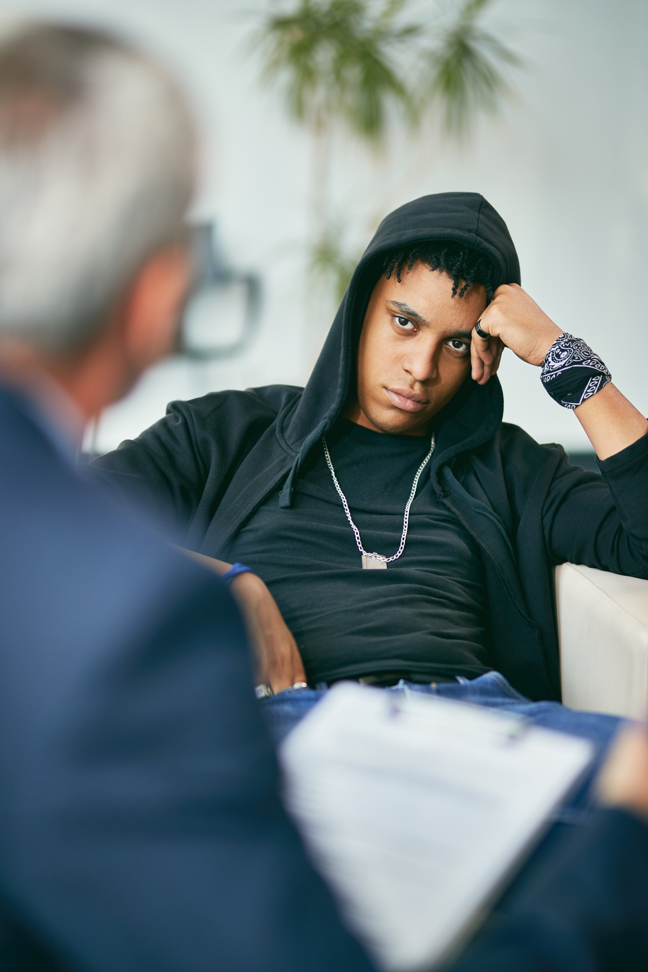 Black male adolescent listening to his counsellor during therapy session at psychotherapist's.