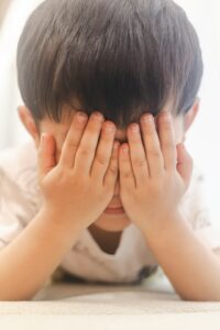 Niño tapándose la cara con las manos